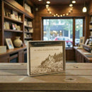 Acadia National Park  box on a wooden table with bookshelves and a window in the background.
