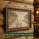 Framed artwork of a father and son fishing with a scenic background, displayed on a wooden wall.