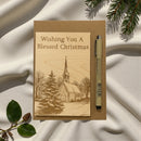 Card with 'Wishing You A Blessed Christmas' text and a pen on a textured fabric background.