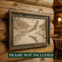 Wooden plaque with engraved design of eagles over a river and text, mounted on a log wall.