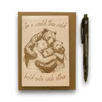 Wood with bear illustration and text 'In a world this wild, hold onto each other' on a white background.