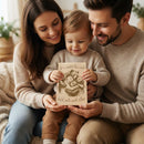 Family of three holding a book together in a cozy indoor setting