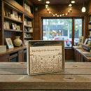 Wooden box with engraved design and text on a wooden table in a cozy indoor setting.